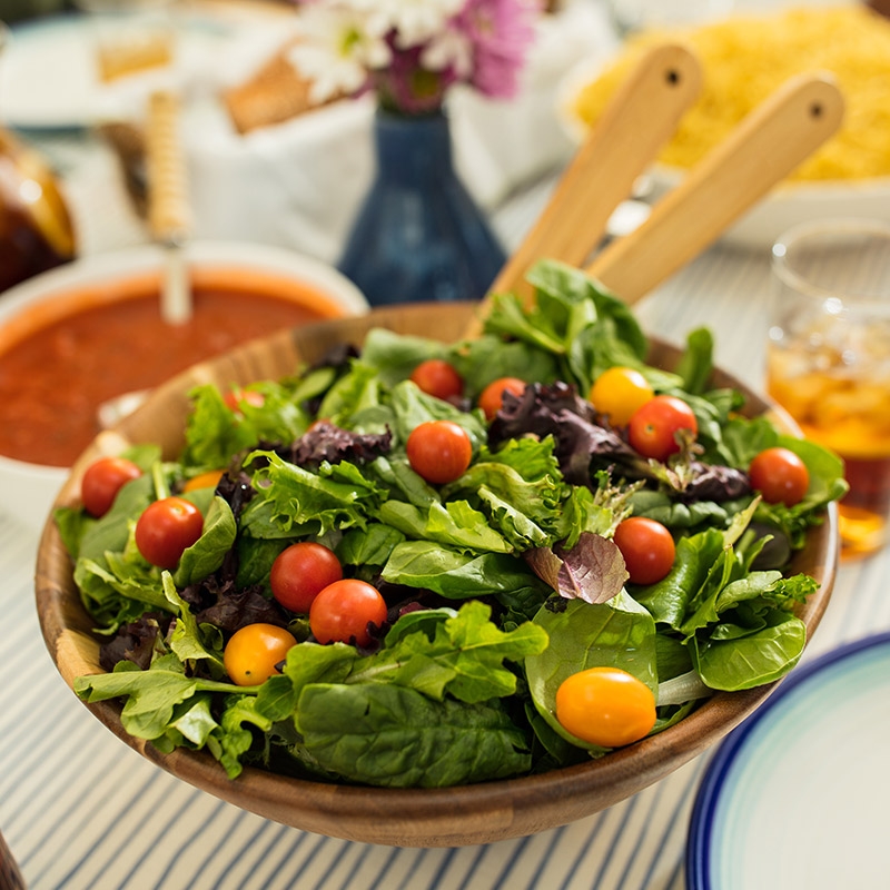 A nutrient dense bowl of salad sits on a table surrounded by low-sugar food options