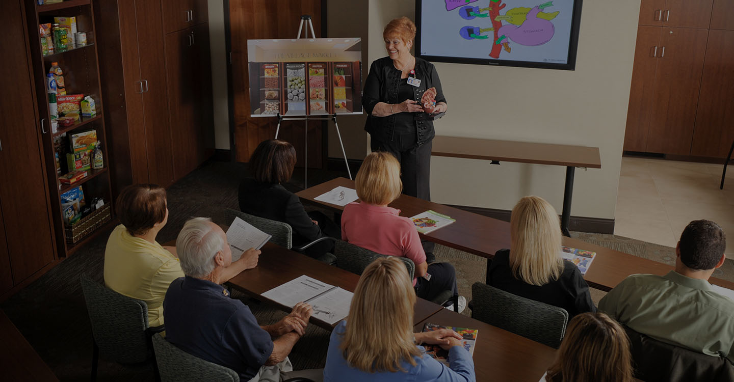 A woman in a black suit teaching a classroom of students about diabetes treatment options