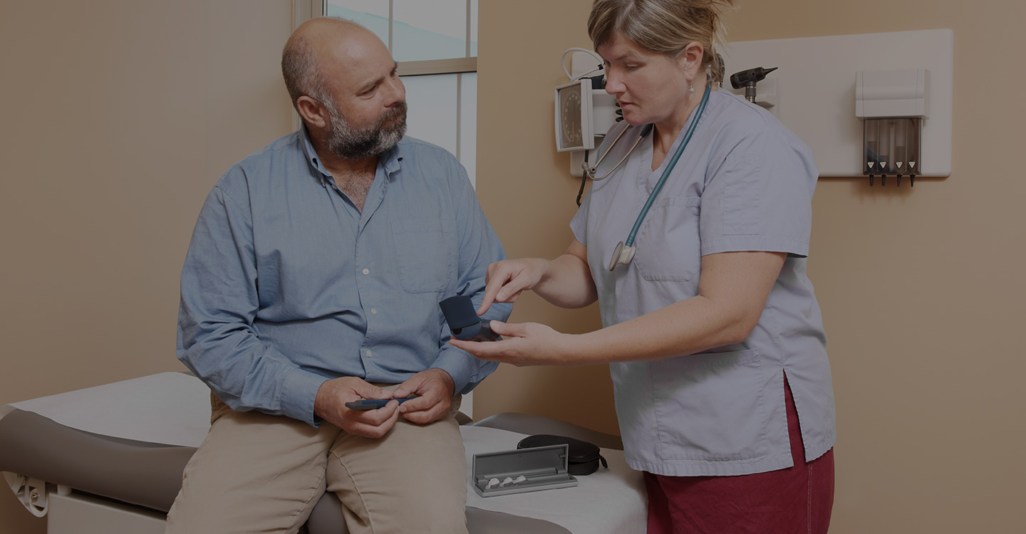 Nurse demonstrates how to use a blood sugar monitor and insulin injection pen to a diabetic patient in a clinical care office