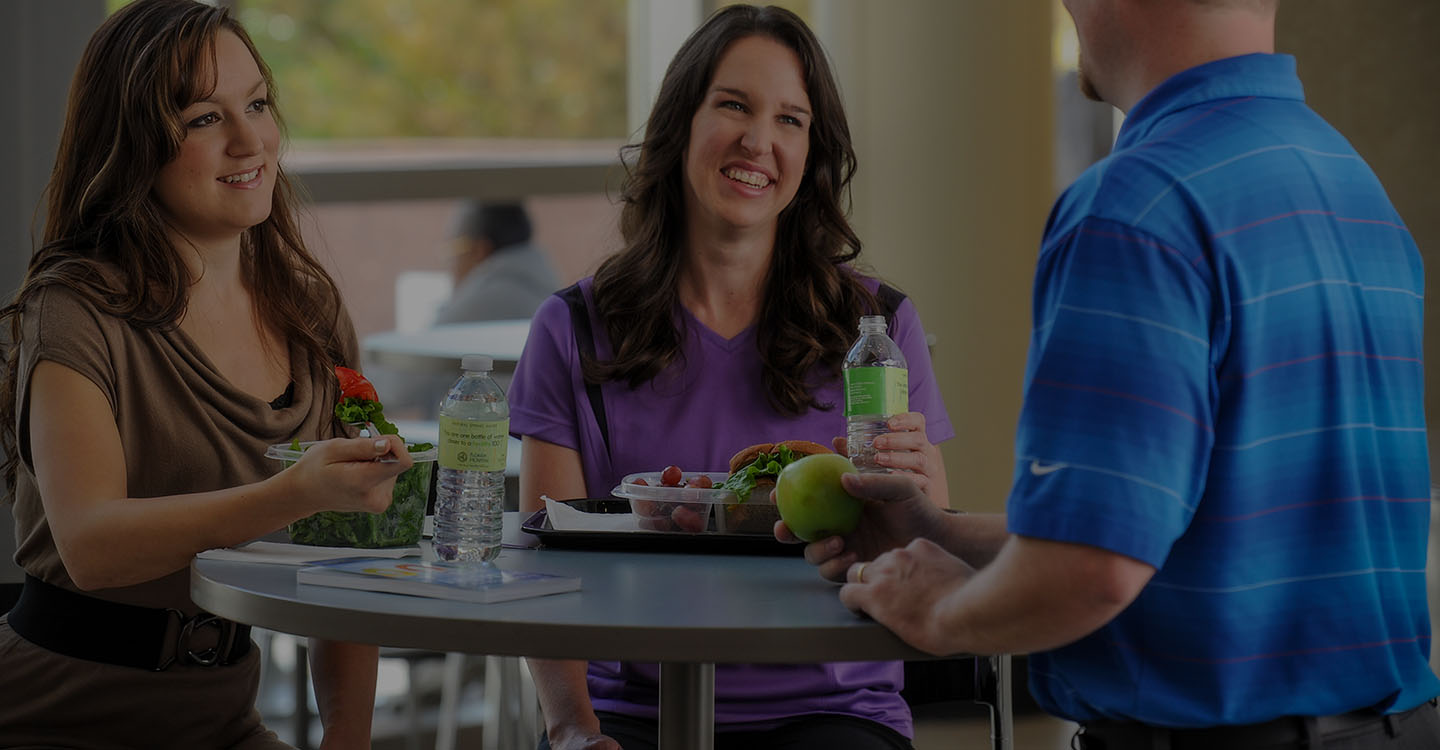 Three smiling employees enjoy a healthy lunch