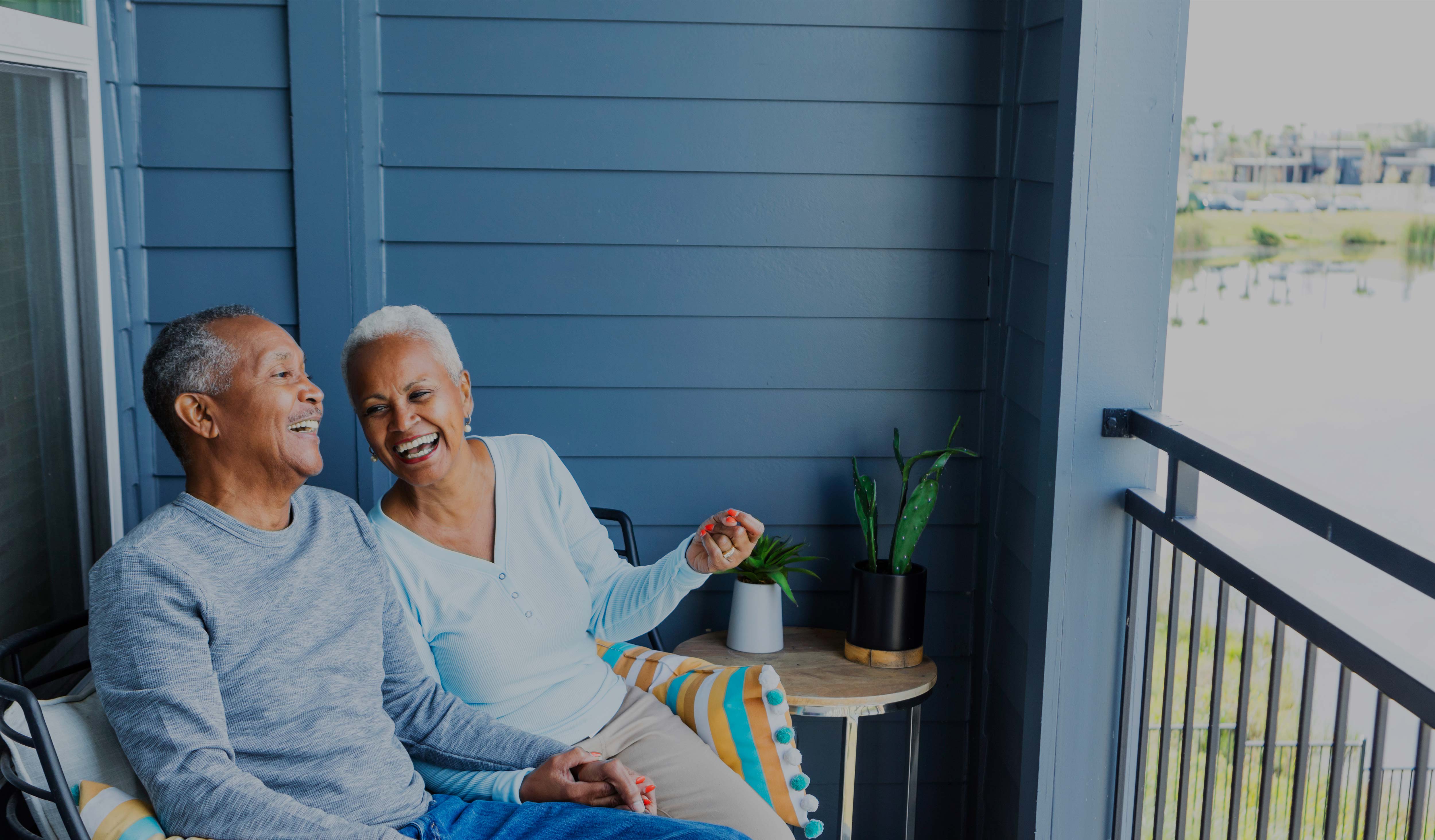 Couple laughing while sitting on porch.