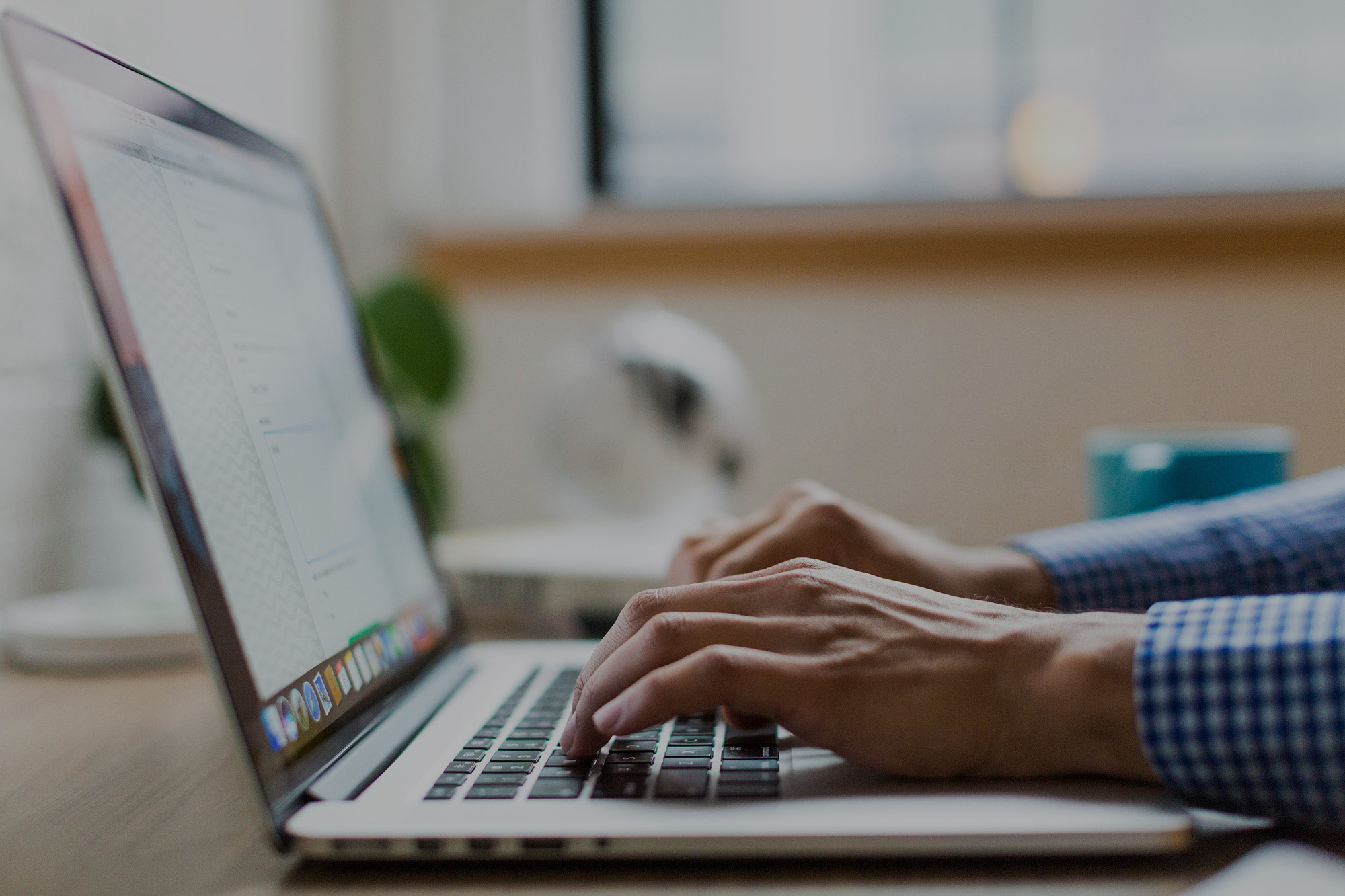 A close-up image of hands typing on a laptop.